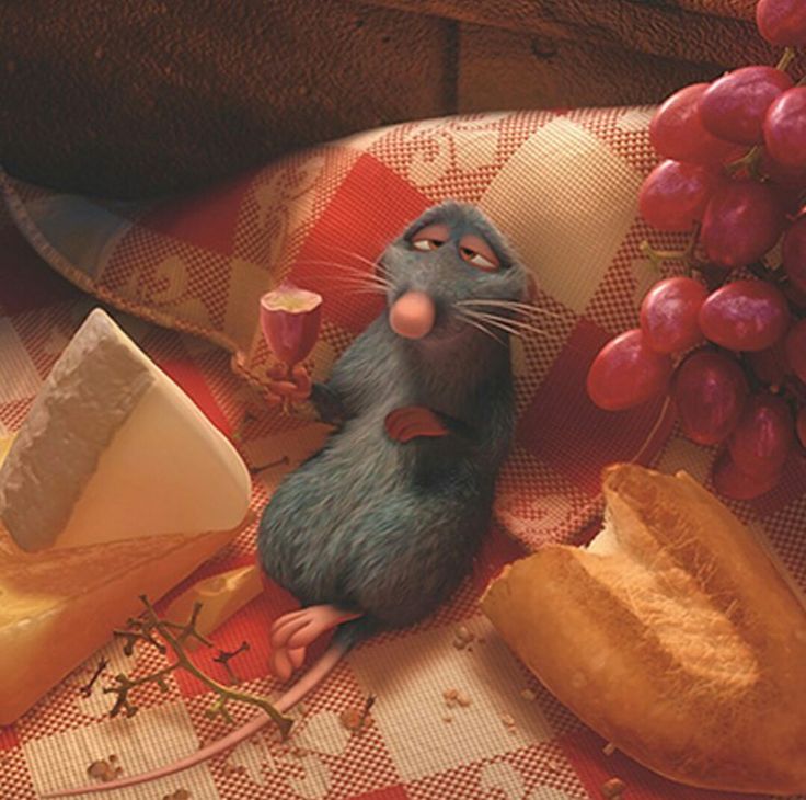 a mouse sitting on top of a table next to bread and grapes