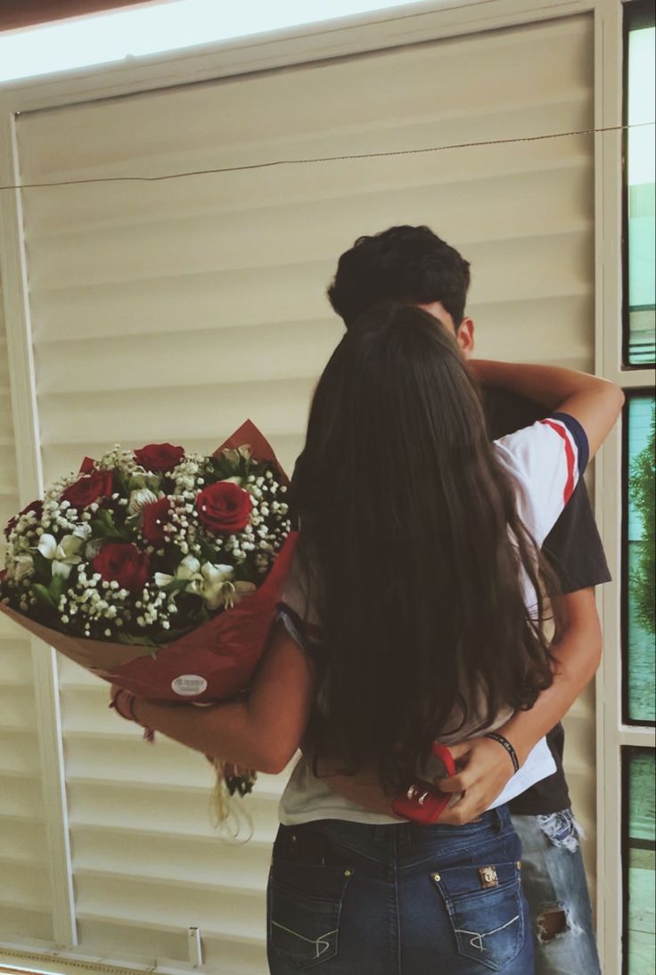 a man and woman standing next to each other with flowers in front of their backs