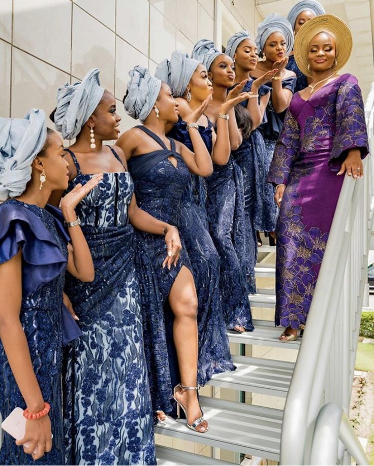 a group of women in blue dresses standing on steps with their hands up to their mouths