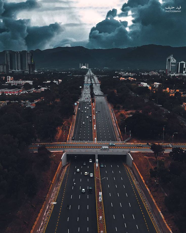 an aerial view of a highway in the middle of a city with dark clouds overhead