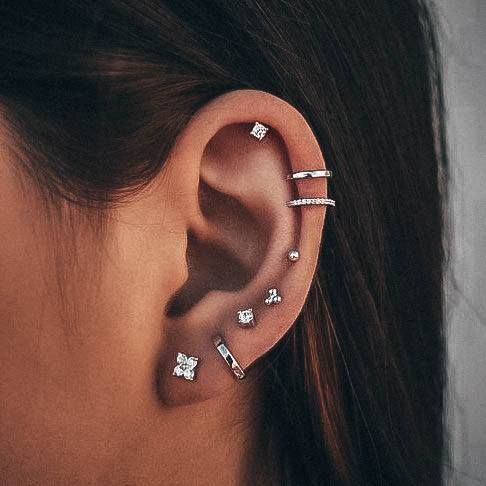 a woman's ear with three different piercings on the middle and one behind her ear