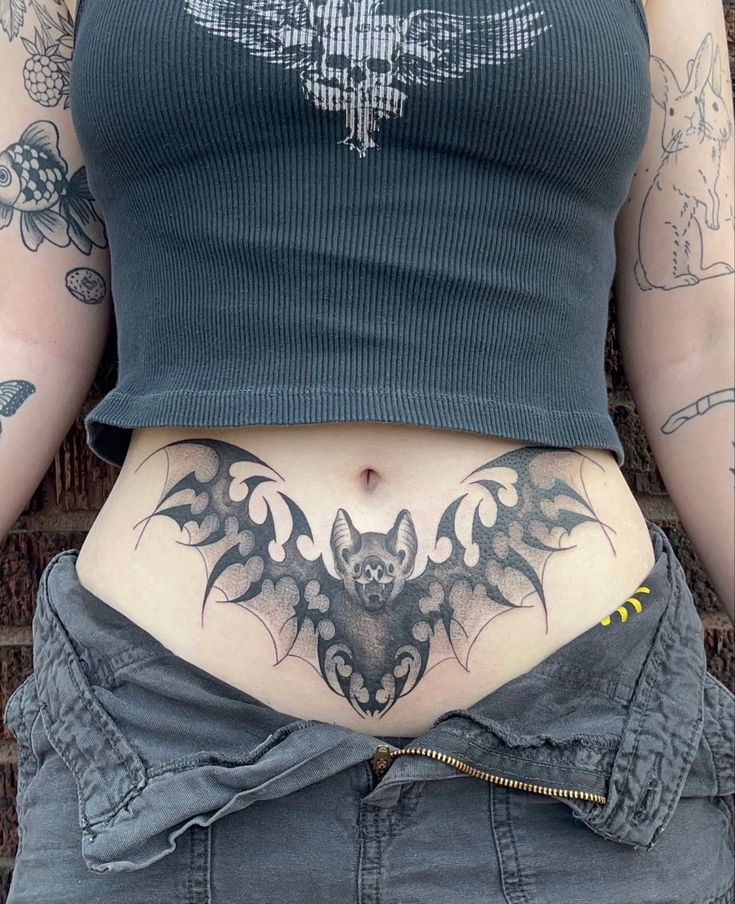 a woman's stomach with a bat tattoo on her lower body and the bottom part of her abdomen