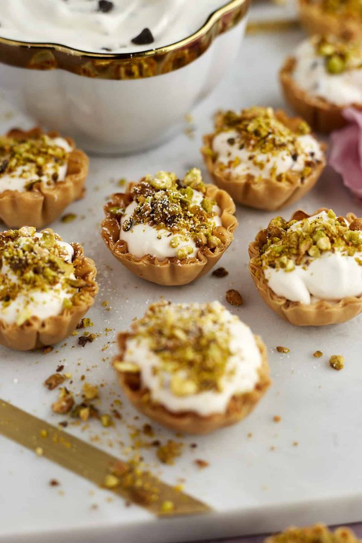 small desserts with white frosting and sprinkles on a tray next to a bowl