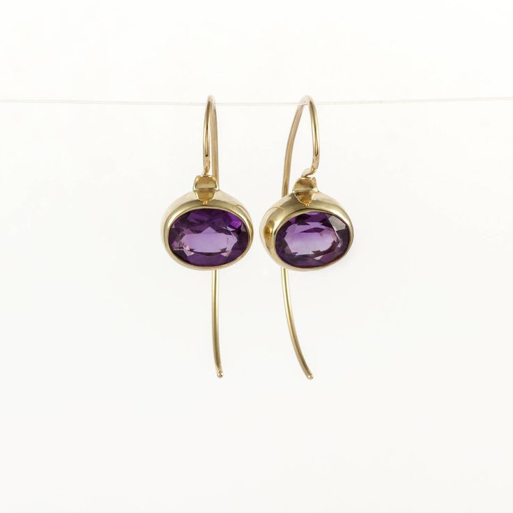 These are dazzling purple Amethyst earrings, handmade of yellow 14k solid gold. The beautiful faceted amethyst gemstones are set in a bezel with an open back so light comes through the stone enhancing its color and beauty. Earrings have a highly shiny finish. The combination of the stunning purple color of the amethyst and the yellow gold is eye catching. These minimalist sparkling earrings will add a chic look to your appearance. Silicon ear backs are included for safety. Total length of the ea 14k Yellow Gold Gemstone Earrings, Modern Purple Gemstone Earrings, Purple Oval Fine Jewelry Earrings, Purple Gemstone Earrings For Everyday Wear, Gold Amethyst Dainty Earrings, Everyday Purple Gemstone Earrings, Dainty Purple Round Earrings, Formal Amethyst Drop Earrings, Amethyst Briolette Earrings For Formal Occasions