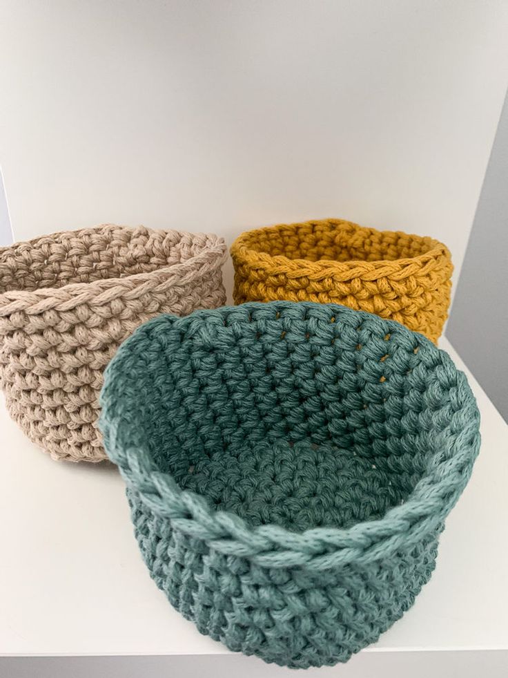 three crocheted baskets sitting next to each other on a white counter top,