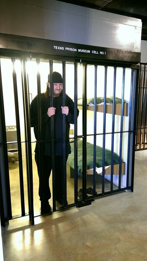 a man standing behind bars in an jail cell