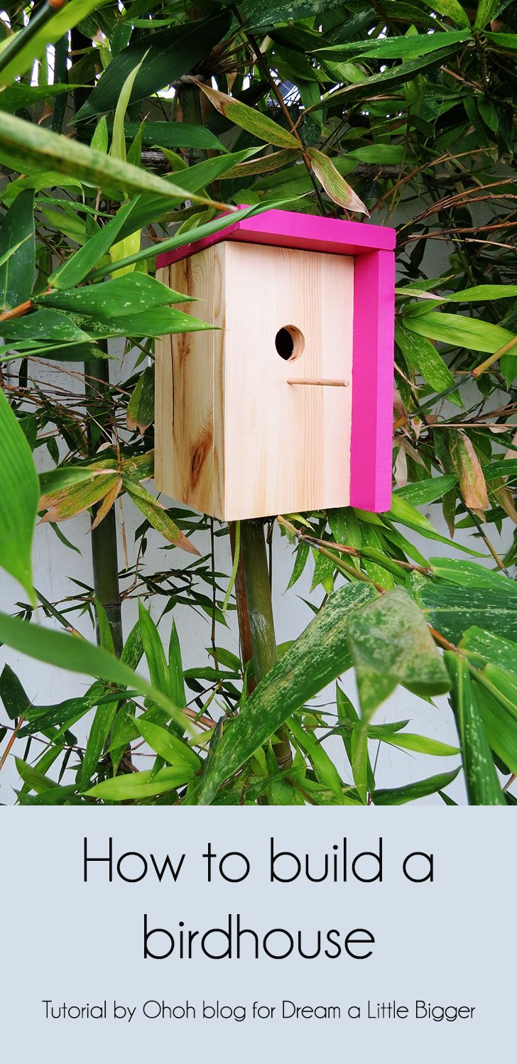 a pink birdhouse sitting on top of a tree