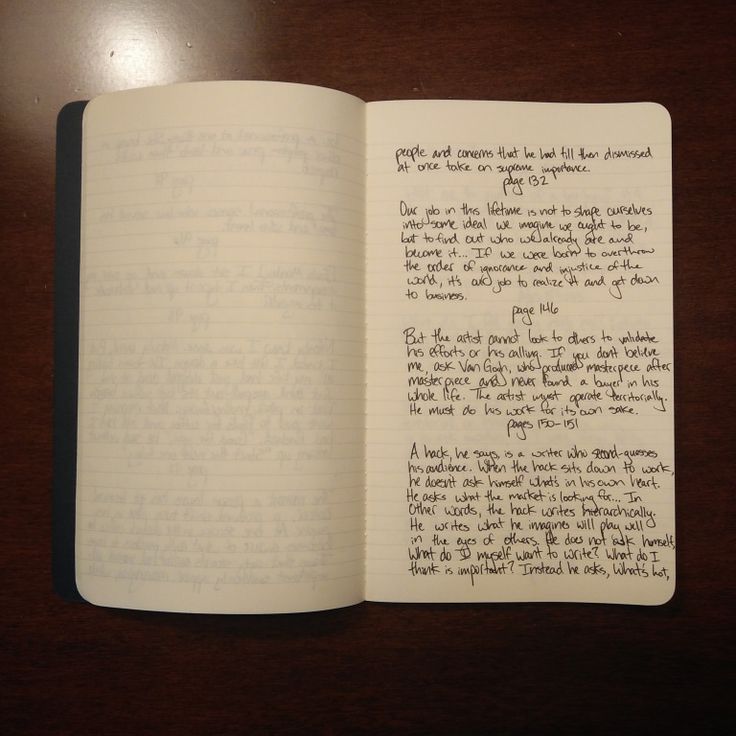 an open notebook with writing on it sitting on top of a wooden table next to a cell phone