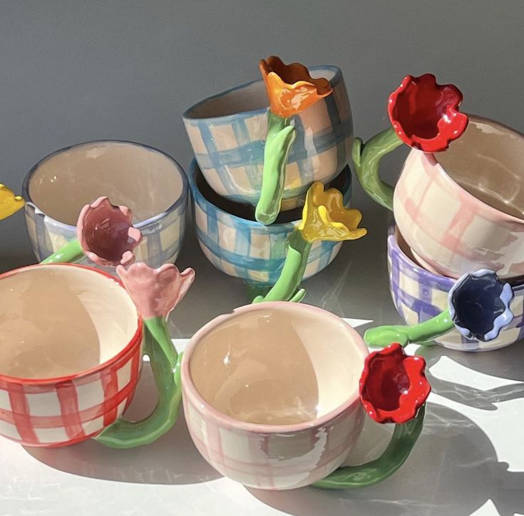 several ceramic bowls with flowers in them sitting on a table