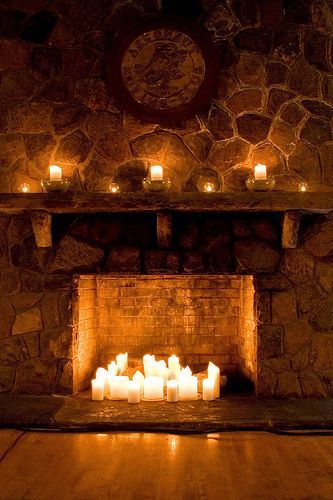 candles are lit in front of a stone fireplace