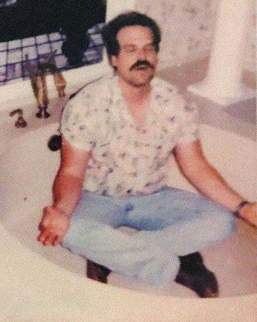 a man sitting in the middle of a bathroom sink