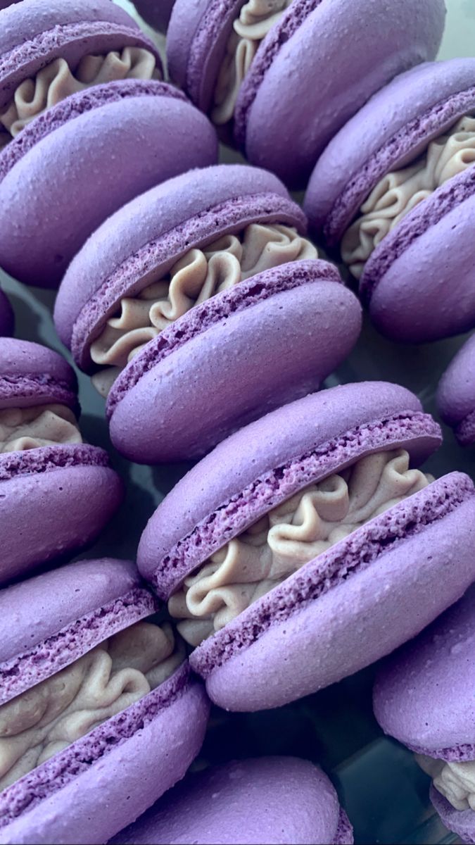 purple macaroons with white frosting are arranged on a green platter and ready to be eaten