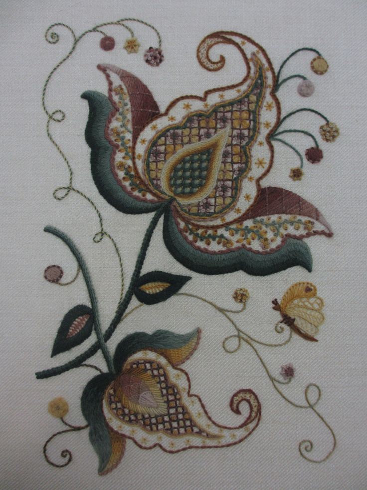 an embroidered piece with flowers and leaves on it's side, in the shape of a flower