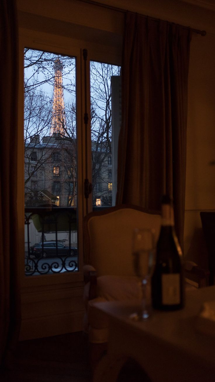 the eiffel tower is seen through an open window in this dimly lit room