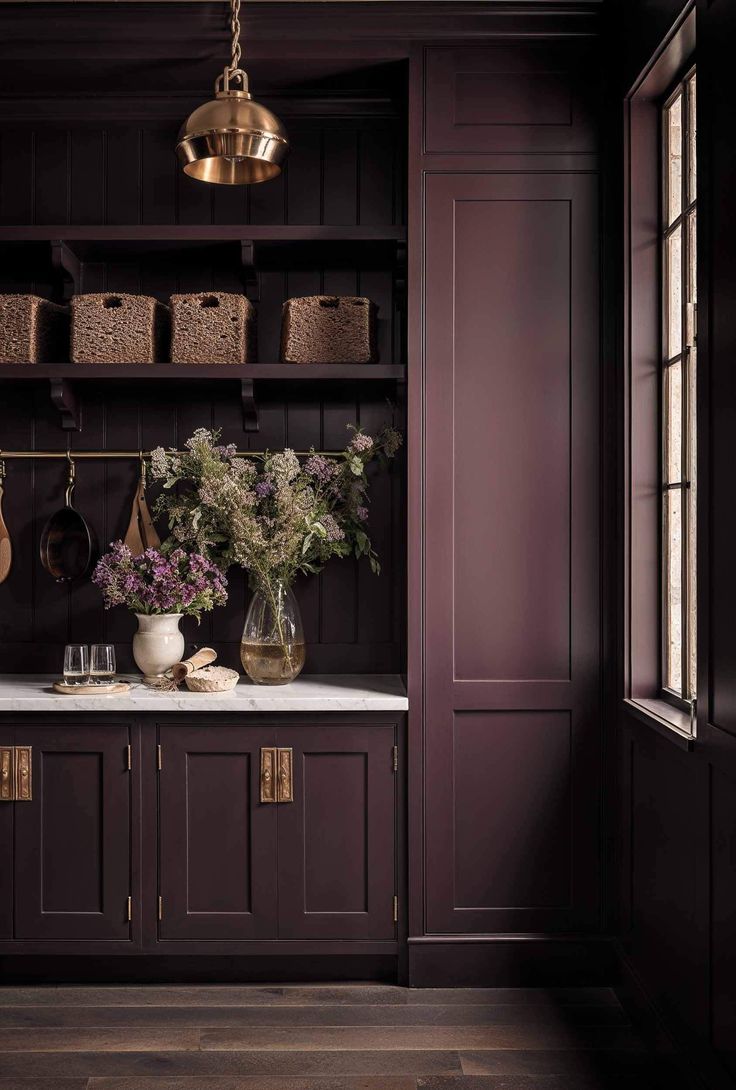 a kitchen with dark wood cabinets and white marble counter tops, brass hanging lights above the sink