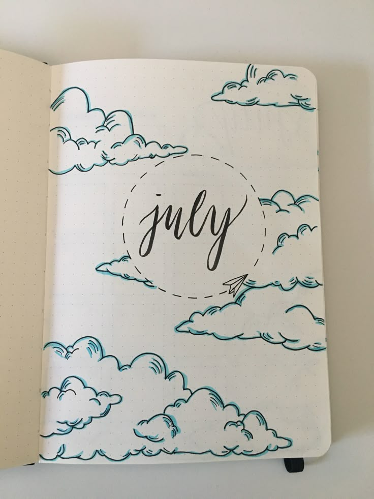 an open notebook with the word july written in cursive writing and clouds on it