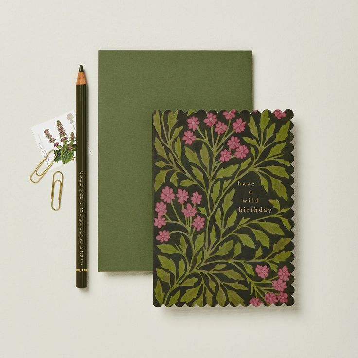 a notepad and pen sitting on top of a desk next to a notebook with flowers