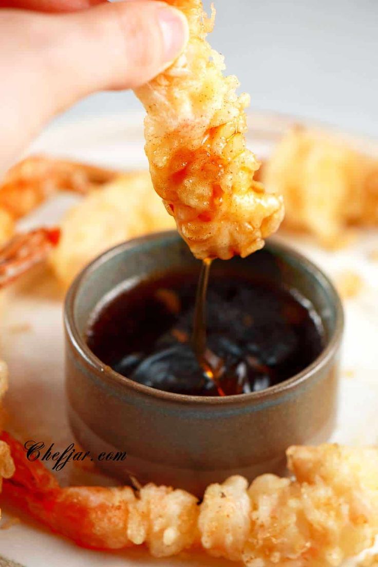 a person dipping sauce onto some shrimp sticks