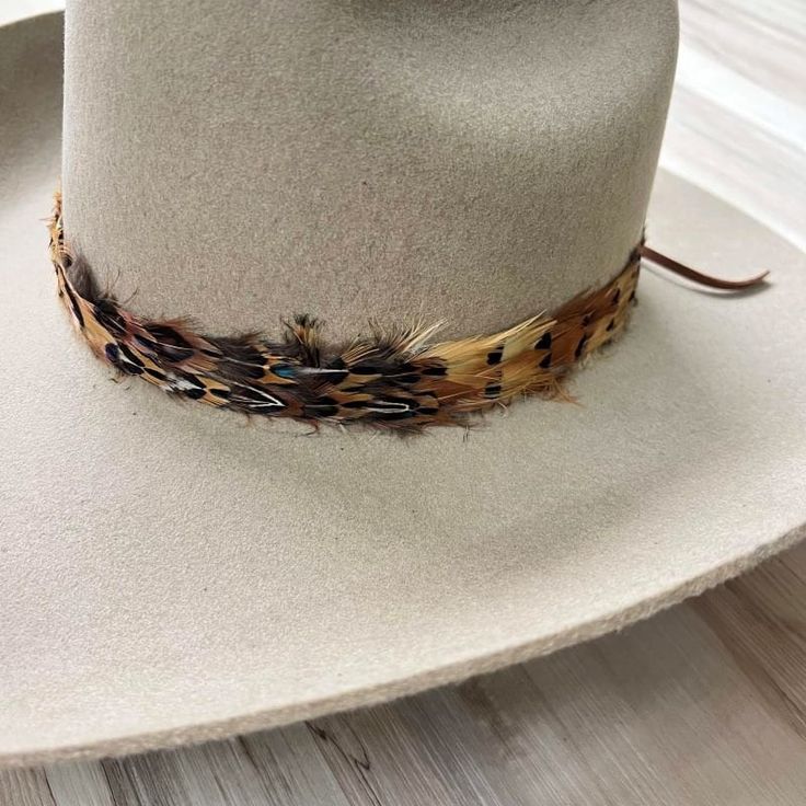 Natural feather hat band. Adjustable with a leather tie. Natural colored feathers Adjustable hatband Approx. 1 inch wide *This product is for 1 single hat band. Hat not included. Rustic Adjustable Brown Top Hat, Adjustable Hat Bands For Country Events In Fall, Adjustable Brown Hat Bands For Fall, Adjustable Brown Hats For Hunting, Adjustable Country Hat Bands For Fall, Adjustable Top Hat For Country Events In Fall, Adjustable Brown Hat Band For Country Events, Adjustable Flat Brim Hats For Hunting, Adjustable Flat Brim Hunting Hat