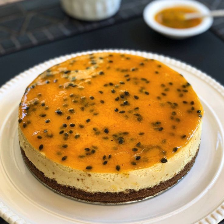 a cheesecake on a white plate with sauce in the background