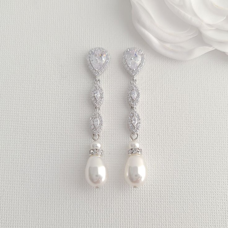 Slim & Long Silver Pearl Earrings for a Perfect Bridal Looks These silver pearl earrings add a delicate finish to complete your bridal and wedding day look. These silver pearl drop earrings are slim and long, measuring 2 inches or 5 cms and about 7mm wide. These silver and pearl earrings are made with marquise cubic zirconia crystal drops with teardrop ear post and teardrop pearl drops in white and cream pearl colors. The combined effect of silver, cubic zirconia sparkle and a soft glow from Pearl Wedding Jewelry Sets, Silver Pearl Drop Earrings, Bridal Jewelry Pearl Sets, Silver Bridal Jewellery, Wedding Jewellery Designs, Rose Gold Pearl, Pearl Bridal Jewelry, Silver Pearl Earrings, Pearl Earrings Wedding