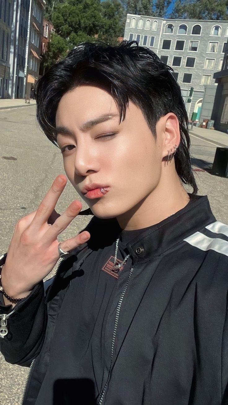 a young man with black hair and piercings making the vulcan sign on his finger