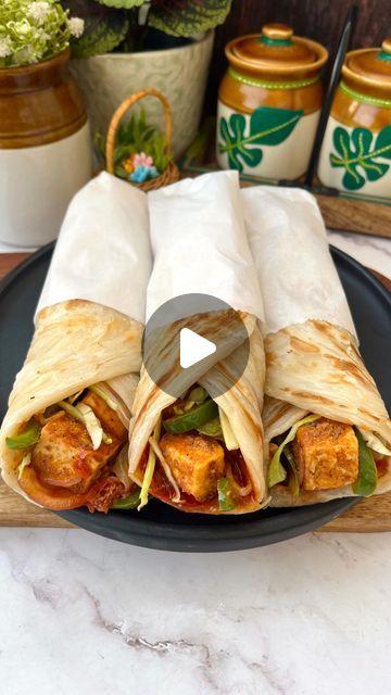 a black plate topped with two burritos on top of a table