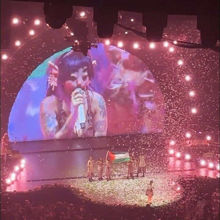 a group of people standing on top of a stage next to a giant tv screen