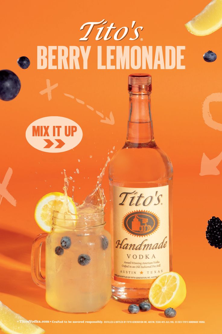 a bottle of lemonade next to a glass filled with liquid and blueberries on an orange background