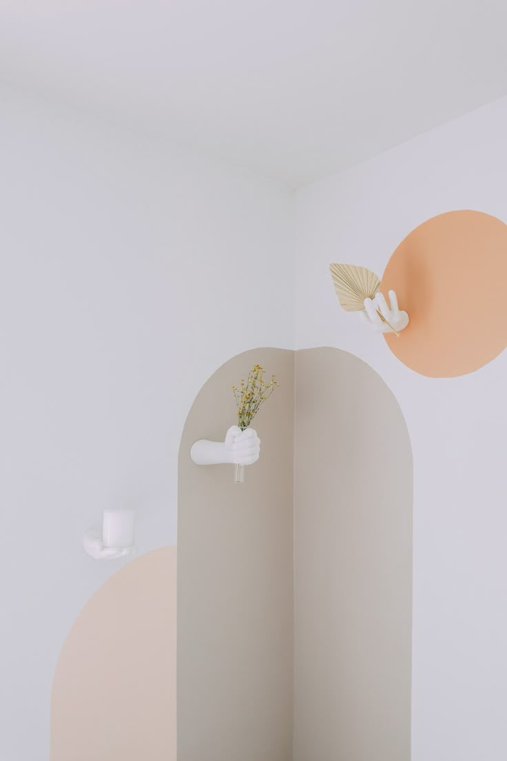 an empty room with white walls and orange circles painted on the wall, along with a vase filled with flowers