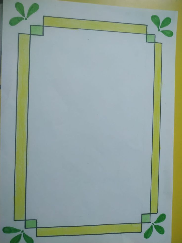 a white paper with green leaves and a yellow border around it on top of a table