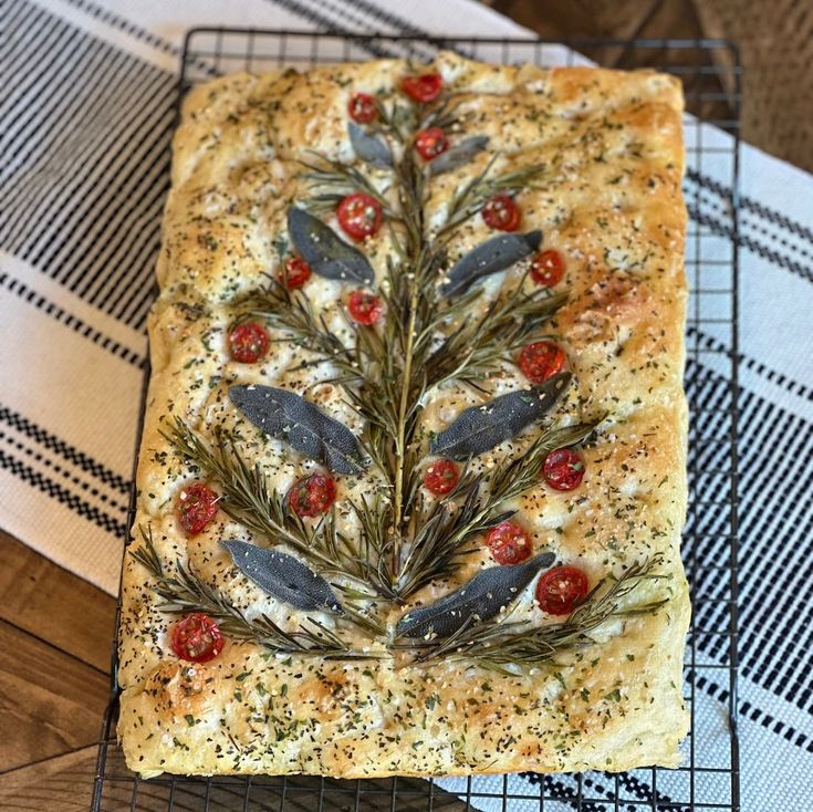 a piece of bread with olives and herbs on it sitting on a cooling rack