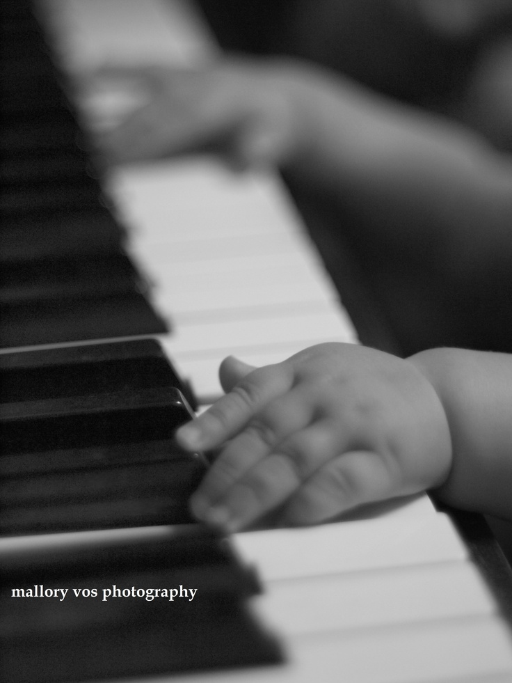 a baby's hand on the keys of a piano