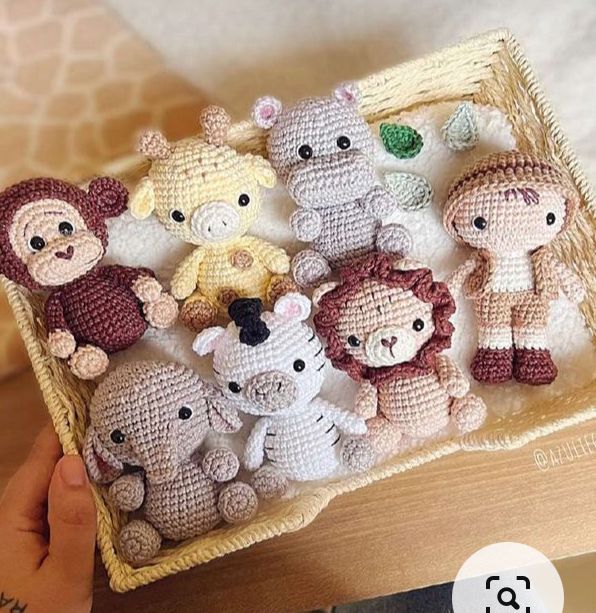 a person holding a basket filled with small stuffed animals on top of a wooden table