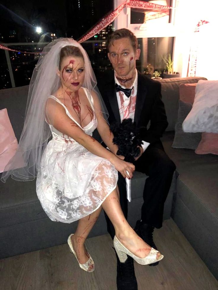 a man and woman dressed up as bride and groom sitting on a couch at night