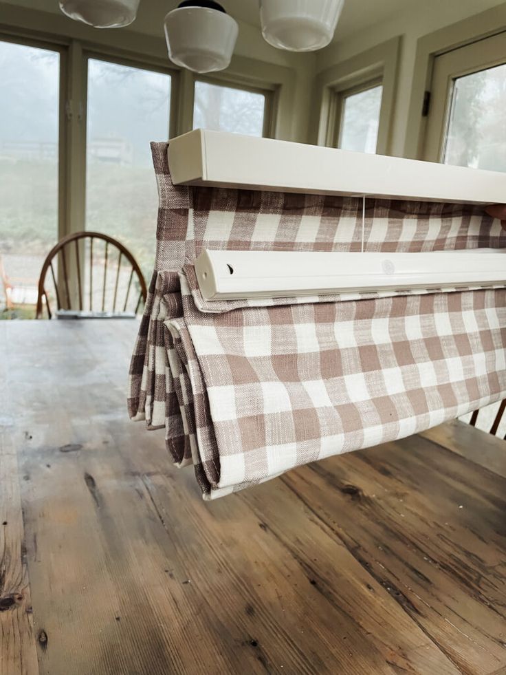 a wooden table topped with a white and brown checkered cloth hanging from the ceiling