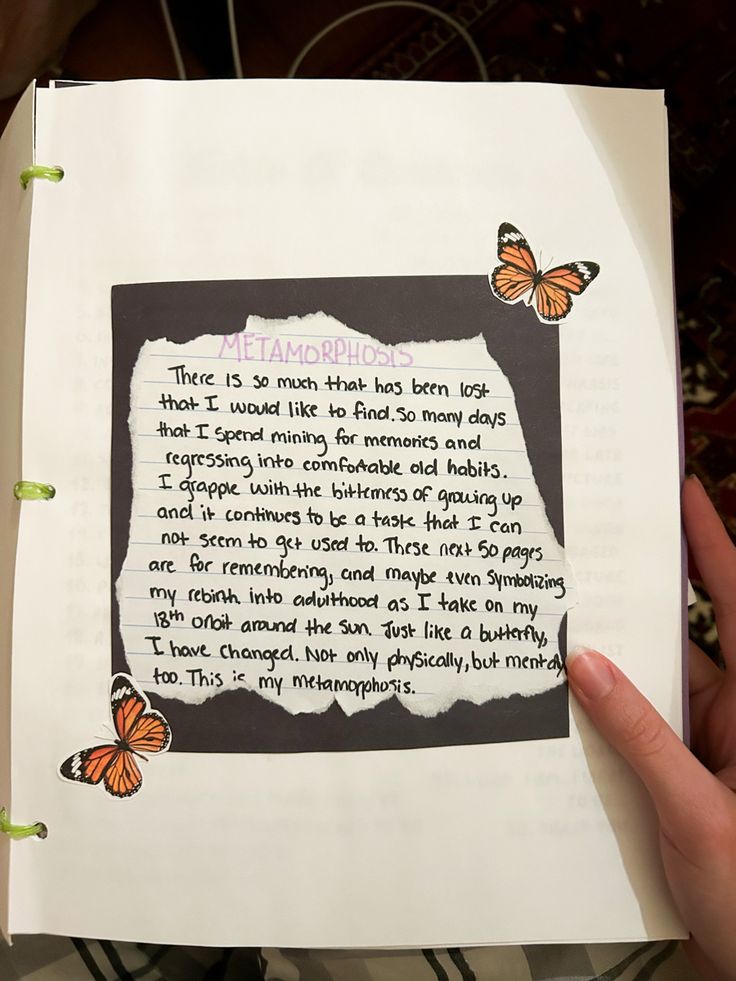 a hand holding up a piece of paper with writing on it and butterflies flying around