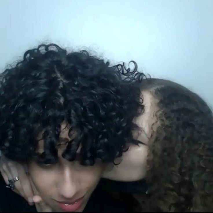 two women with curly hair are kissing each other