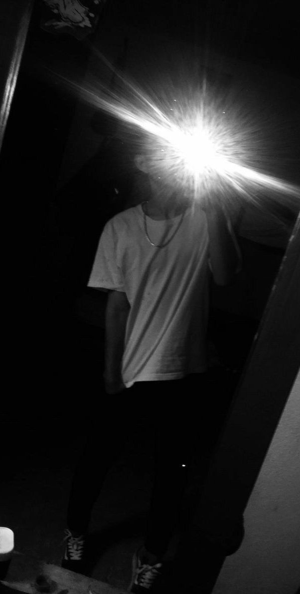 a person standing in a dark room with a light shining on their face and head