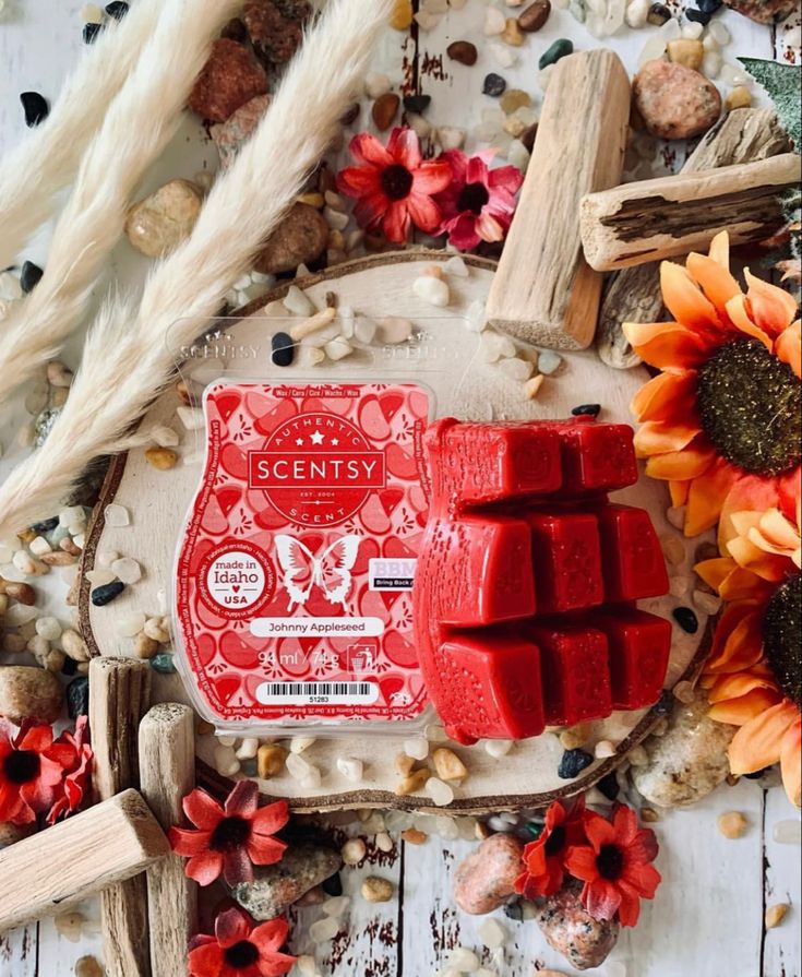 a red wax block sitting on top of a wooden table next to flowers and other items