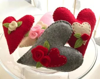 three felt heart shaped pillows sitting on top of a glass plate