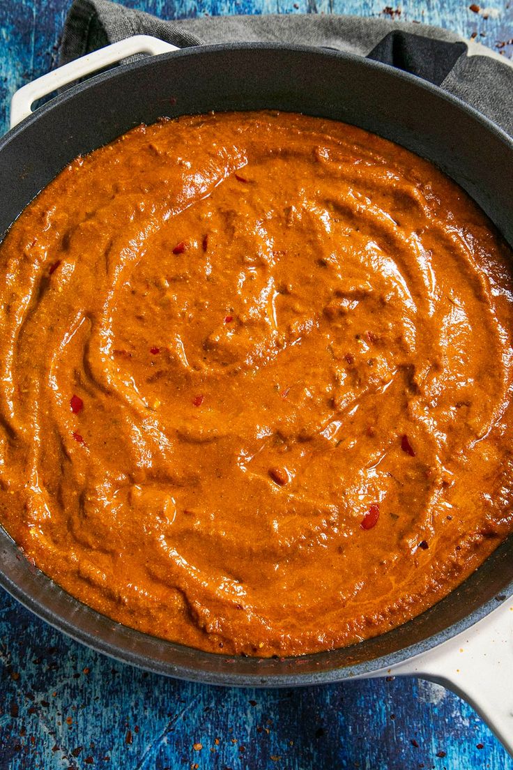 a pan filled with sauce sitting on top of a blue table