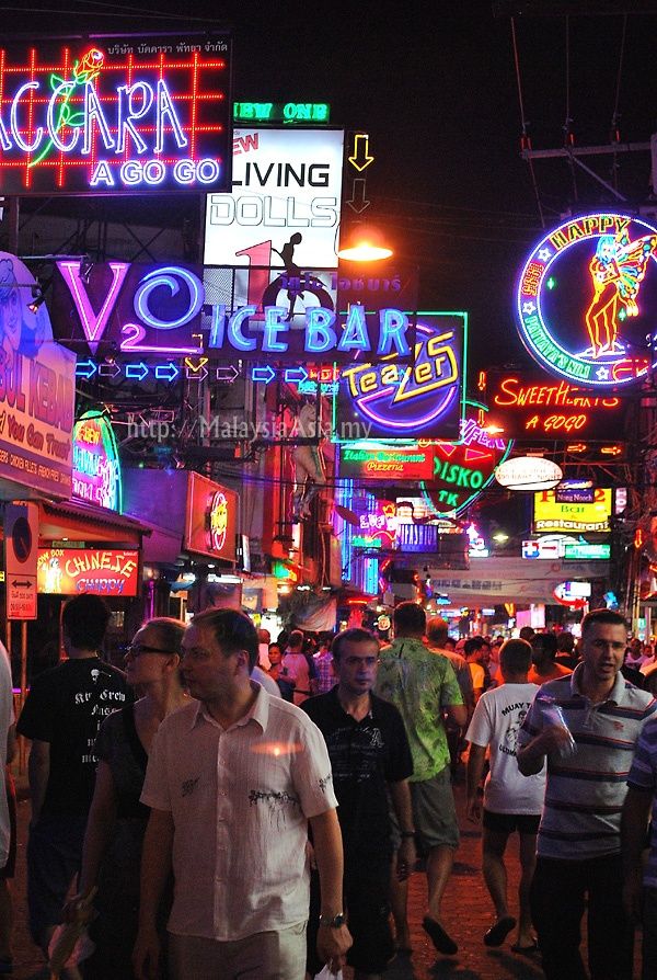 many people are walking down the street in front of neon signs and advertisements at night