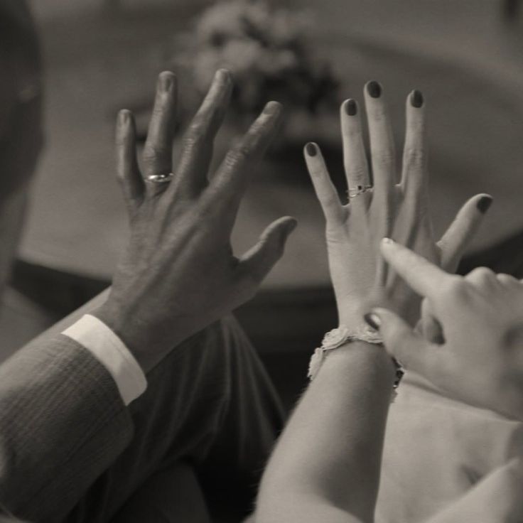 two people with their hands in the air and one person wearing a ring on her finger