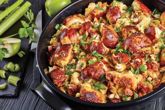 a pan filled with food sitting on top of a table next to green onions and celery