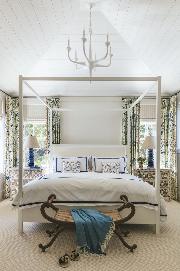 a white bed sitting under a chandelier in a bedroom