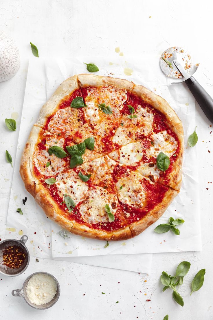 a pizza sitting on top of a white table next to some sauce and pepperoni