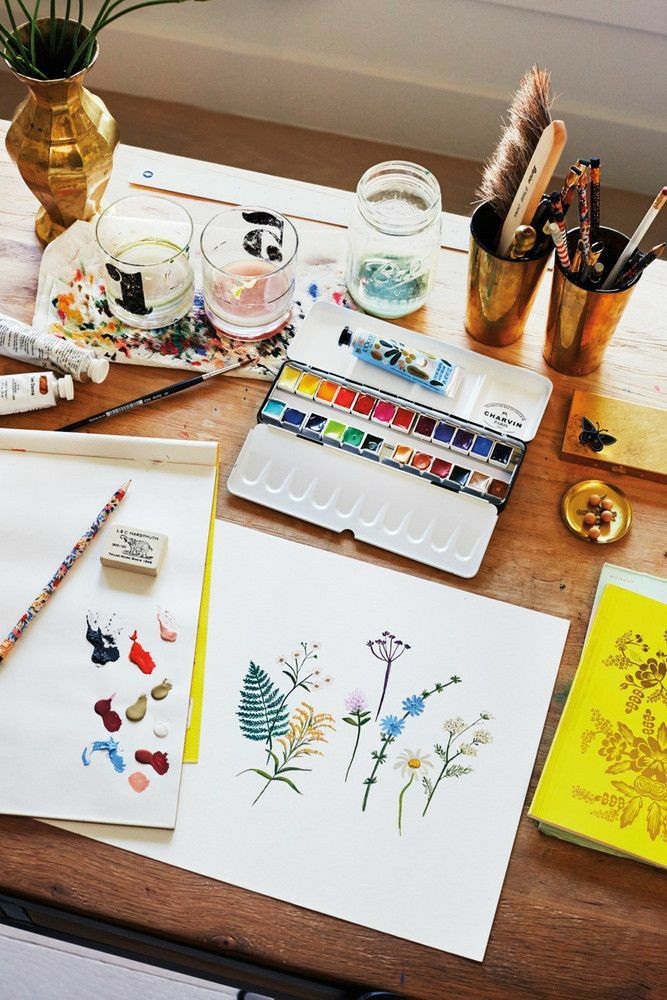 the table is covered with art supplies such as watercolors, paint and brushes