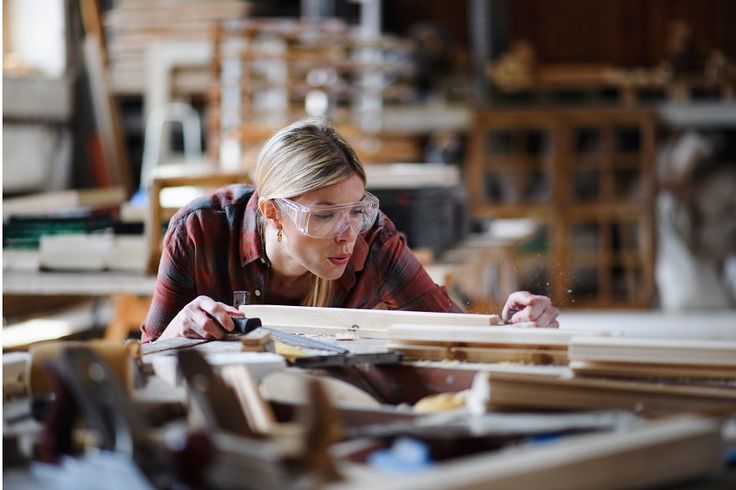 a woman working on woodworking in a workshop