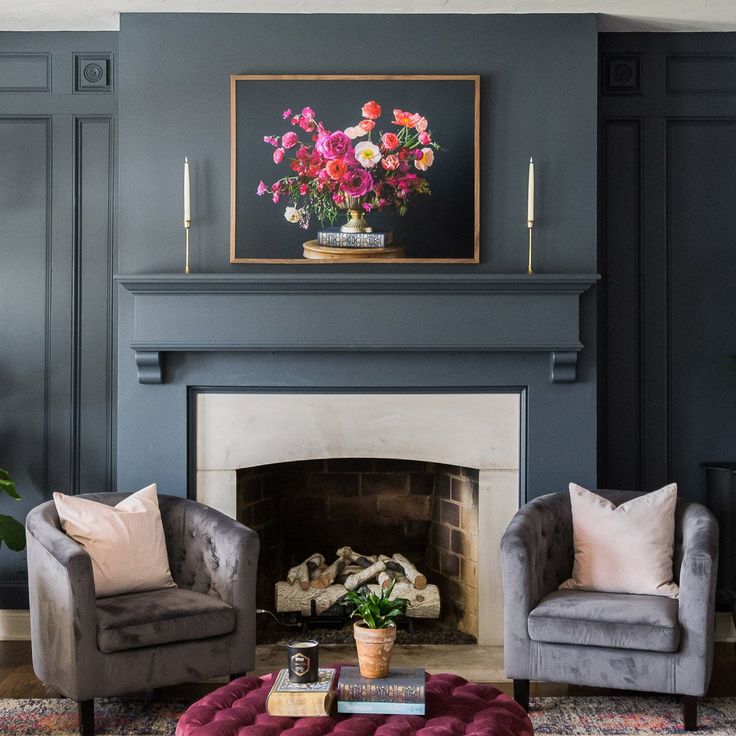 a living room with two chairs and a fire place in front of a painting on the wall